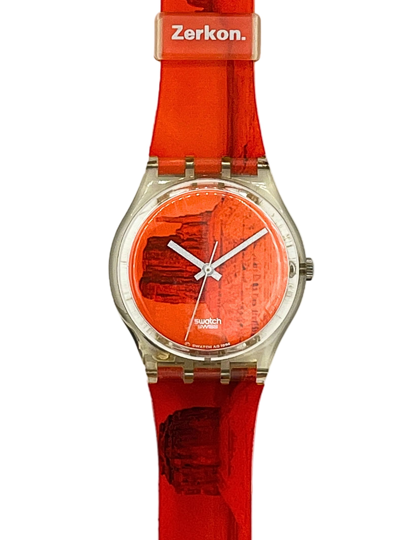 A wristwatch with a bright orange-red silicone strap and matching dial, featuring a silver-tone round case and Swatch branding on the dial and Zerkon on the buckle.
