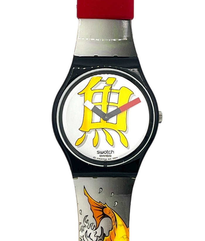 Swatch wristwatch with a black bezel, white dial featuring a large yellow fish symbol, red hands, and a printed koi fish design on a silver and white strap with a red section near the top.