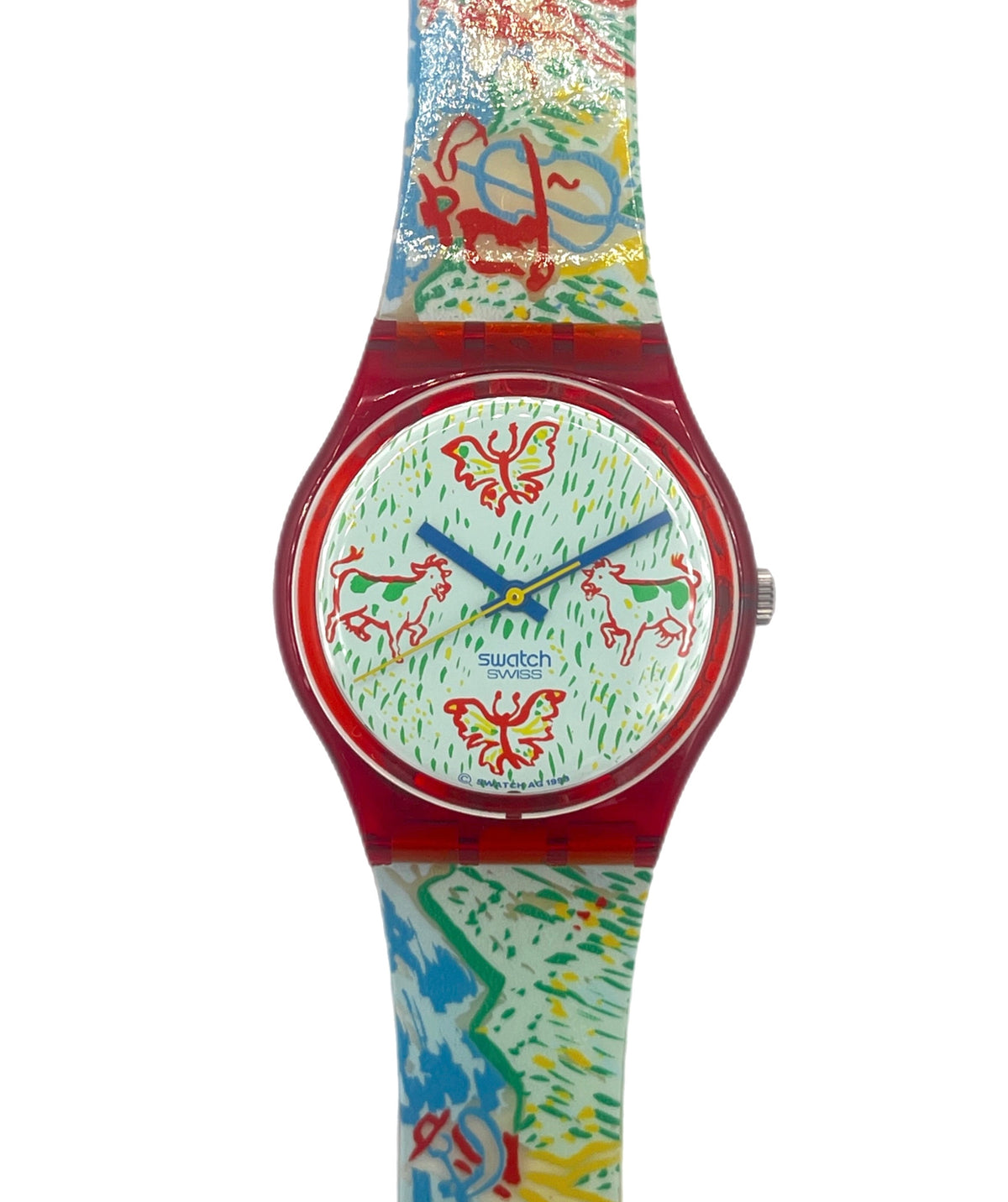 A Swatch wristwatch featuring a vibrant, multicolored abstract pattern on the strap and dial, with a translucent red case and blue hands.