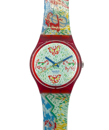 A Swatch wristwatch featuring a vibrant, multicolored abstract pattern on the strap and dial, with a translucent red case and blue hands.