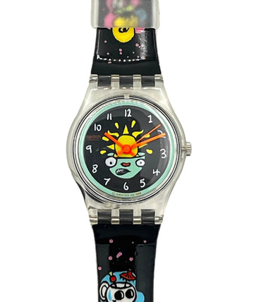 A Swatch wristwatch with a black strap decorated with colorful cartoon characters and pink speckles, featuring a silver-tone case and a black dial with a smiling sun and moon face.