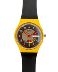 Swatch wristwatch with a bright yellow case, black strap, and a brown dial featuring colorful Swatch logo graphics and a day/date window.
