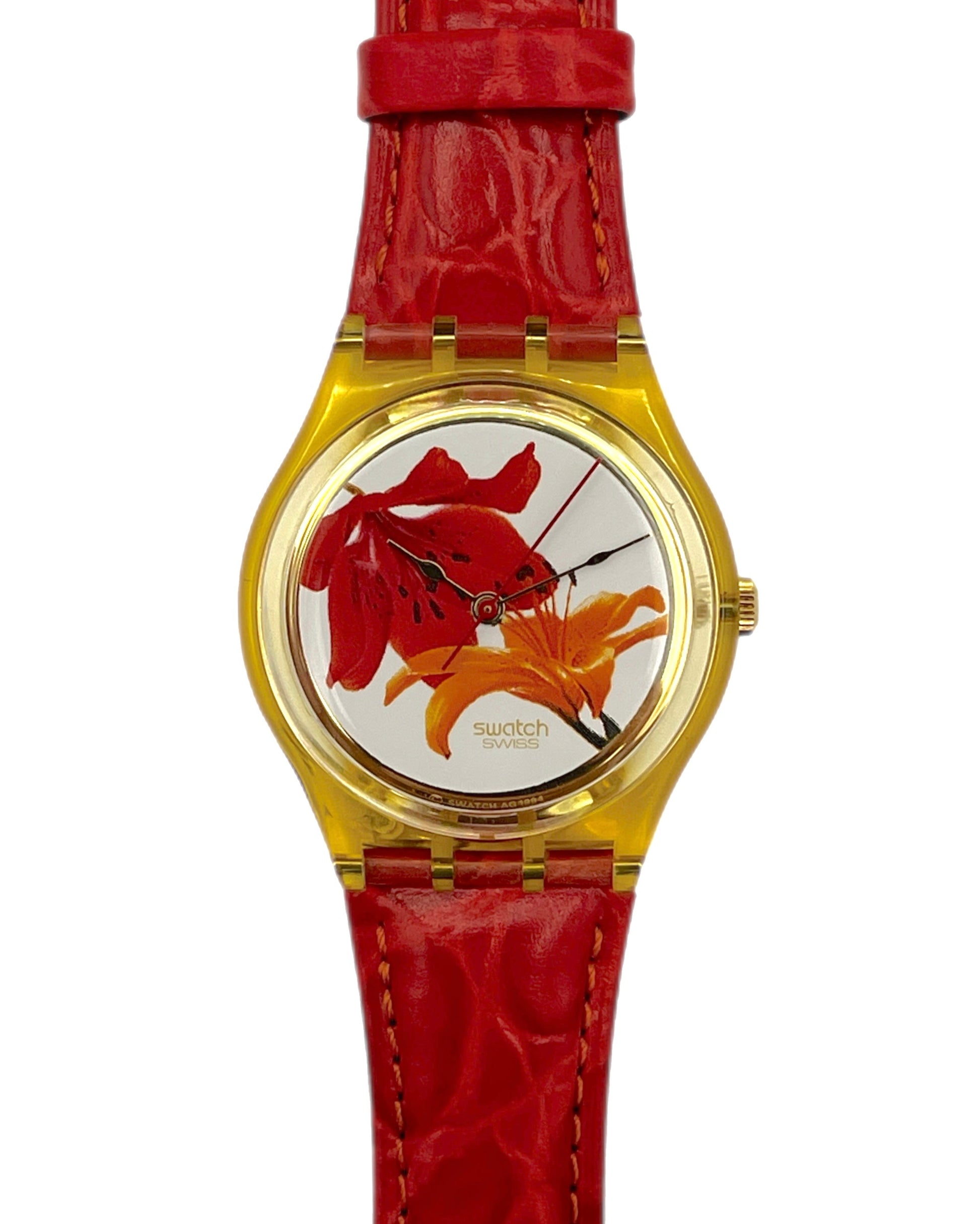 Watch with red strap and floral design on the face against a white background