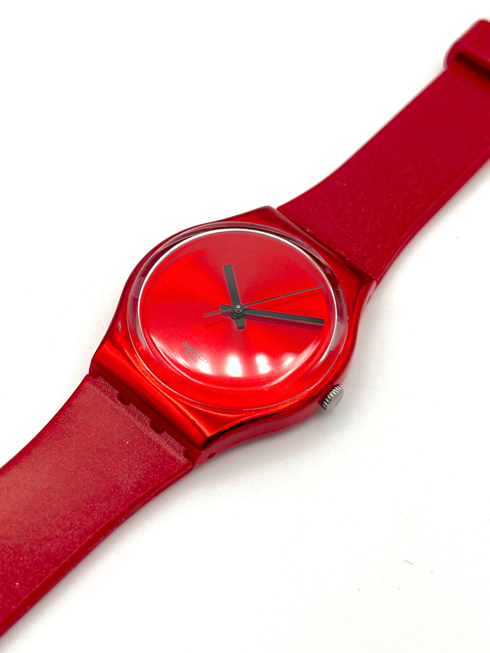 Red wristwatch with a clear face on a white background