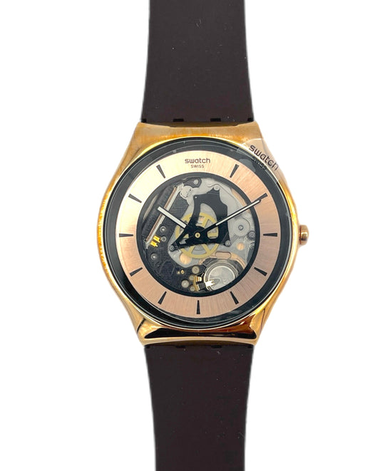 Swatch watch with black strap and gold case on a white background