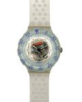 A Swatch wristwatch with a translucent light blue-green bezel, a white textured silicone strap, and a visible mechanical movement inside the clear dial.