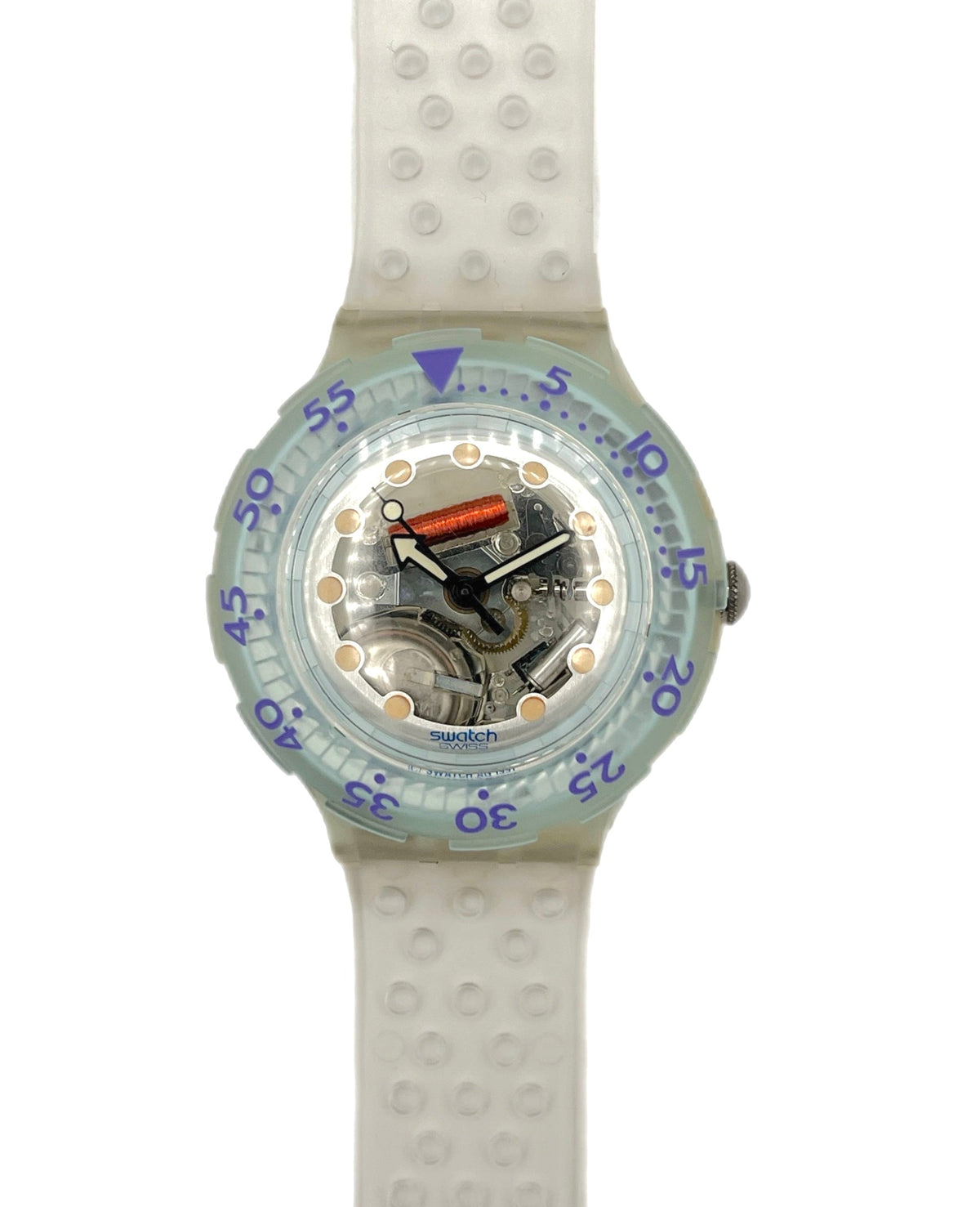 A Swatch wristwatch with a translucent light blue-green bezel, a white textured silicone strap, and a visible mechanical movement inside the clear dial.