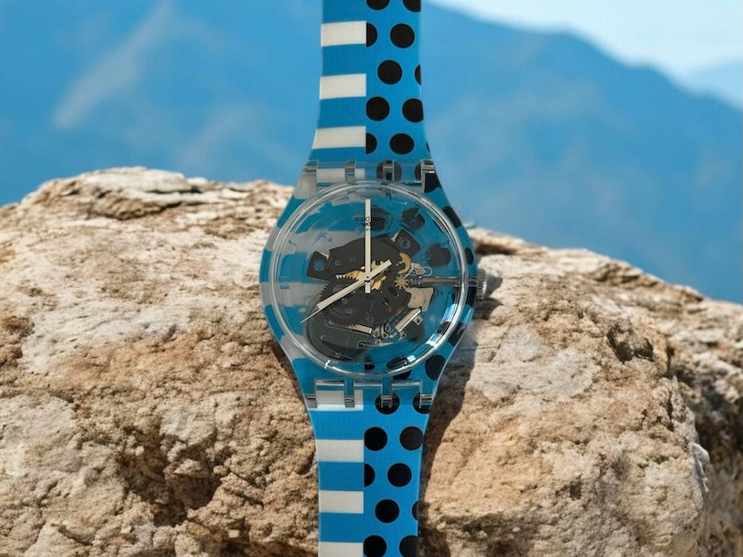 A new, unopened replacement band for a Pop Swatch watch, featuring a vibrant orange textile strap with a matching orange dial, packaged in a clear plastic case.