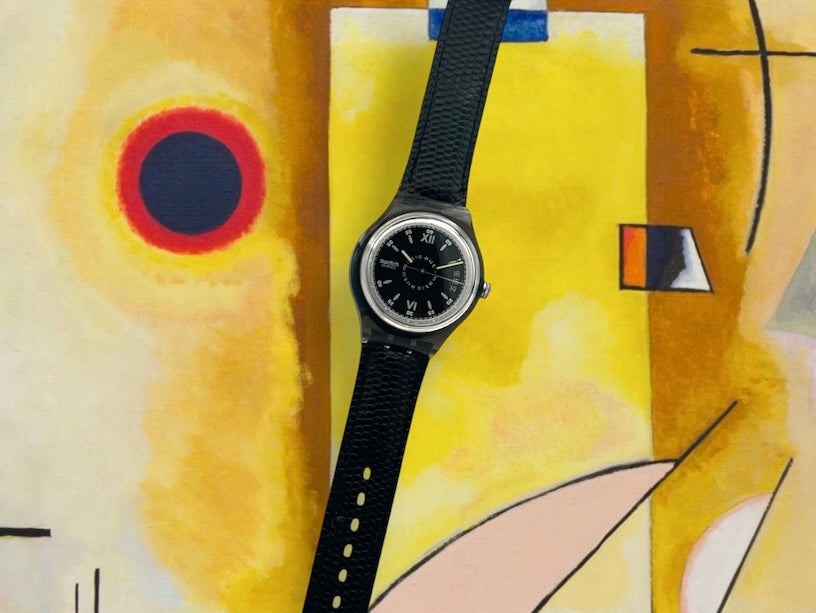 A new, unopened replacement band for a Pop Swatch watch, featuring a vibrant orange textile strap with a matching orange dial, packaged in a clear plastic case.