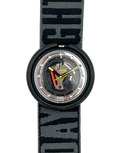 A Swatch wristwatch with a black circular case and a patterned gray and black fabric strap. The watch face is transparent, showing the internal mechanical movement with gold, silver, and red details.