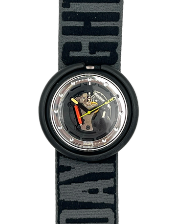 A Swatch wristwatch with a black circular case and a patterned gray and black fabric strap. The watch face is transparent, showing the internal mechanical movement with gold, silver, and red details.