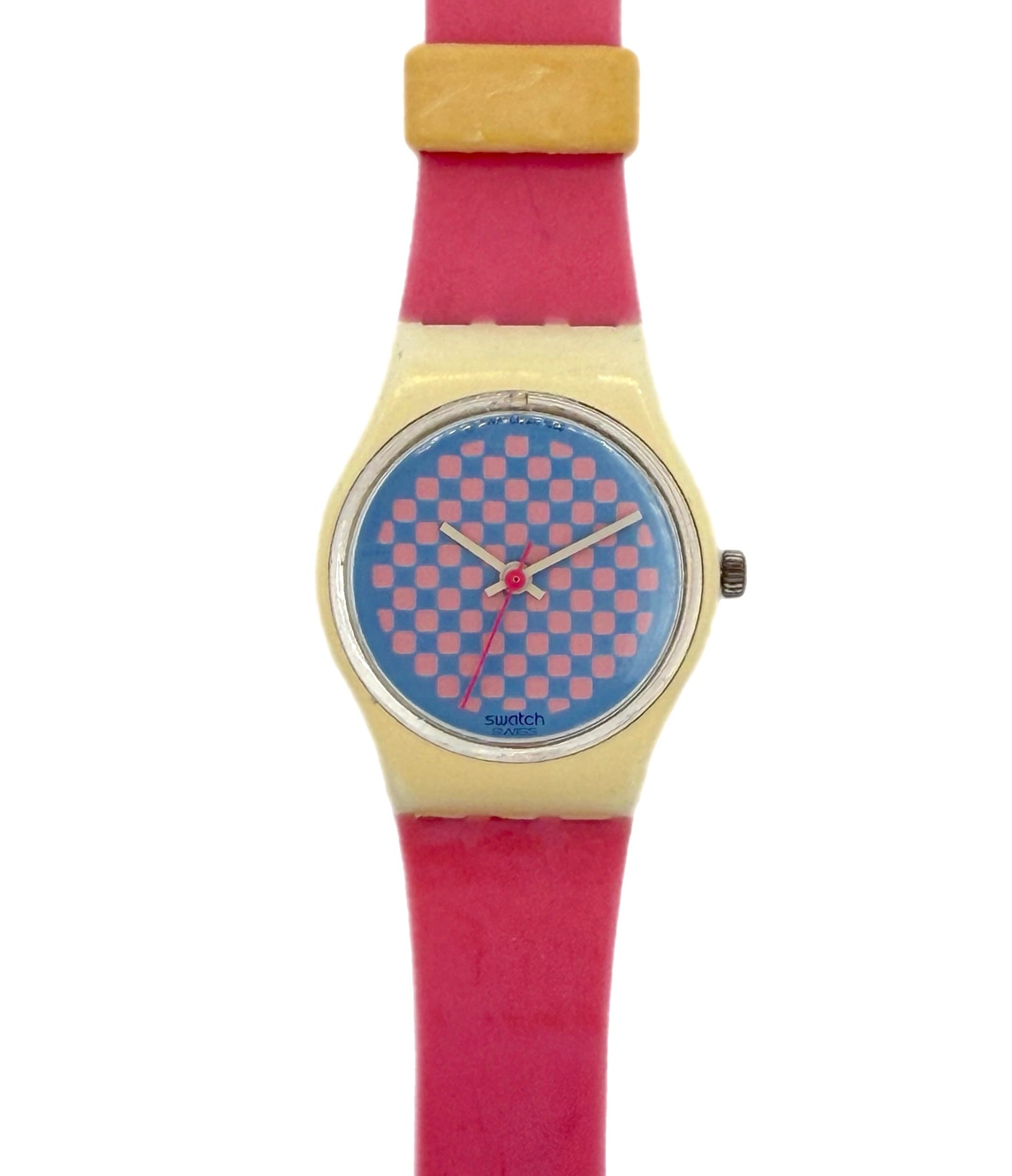 A Swatch wristwatch featuring a bright pink strap, a gold-tone case, and a blue dial with a pink checkerboard pattern.