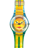 A wristwatch with a colorful striped and plaid strap in yellow, green, and blue, featuring a round clear crystal case and a yellow dial with a stylized face design.