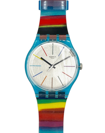 Swatch wristwatch with a bright blue case and a colorful rainbow-striped strap on a light gray background.