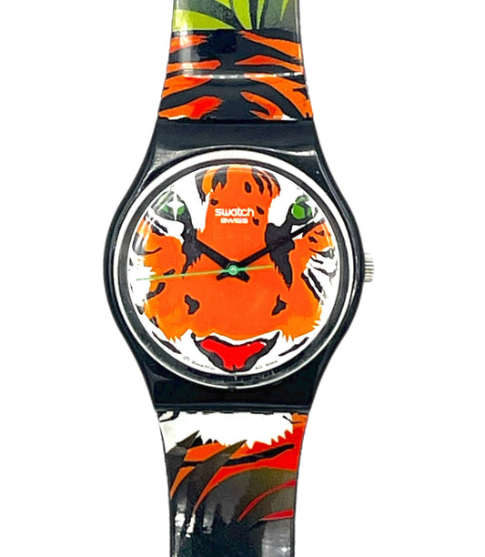A Swatch wristwatch featuring a colorful tiger face design on the dial and a matching tropical print strap with orange, black, green, and white patterns, shown against a plain white background.
