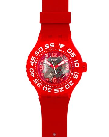 A red Swatch wristwatch with a matching red silicone strap and a skeleton dial showing the inner movement, set against a plain white background.