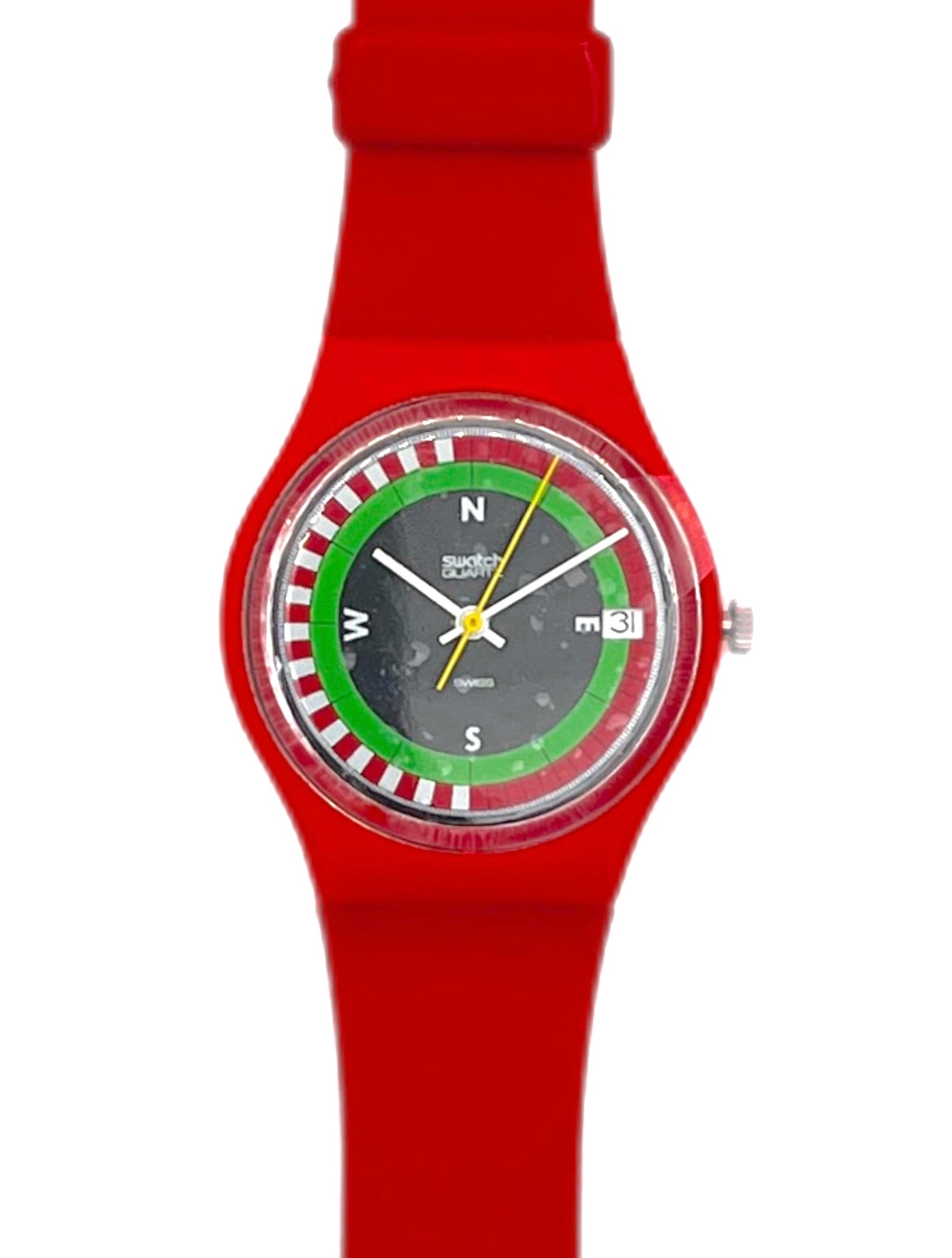 A Swatch wristwatch with a bright red silicone strap and case, featuring a unique dial with a green and red roulette wheel design, white letter markers, and yellow hands on a white background.