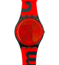 A Swatch wristwatch featuring a bright red silicone strap and matching red dial with black concentric spiral details, black bezel, and bold black lettering on the strap.