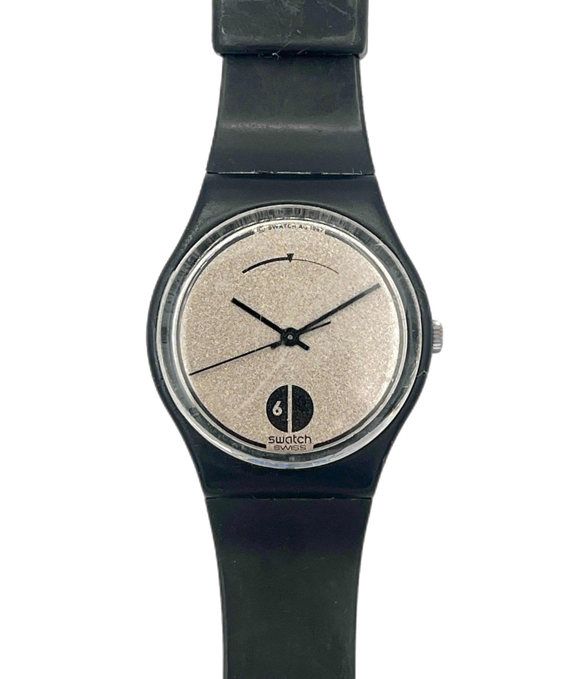 A Swatch watch with a black strap and case, featuring a textured beige dial with black hands and a black logo at the bottom.