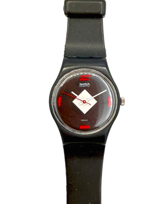 A Swatch Swatch Classic wristwatch with a black silicone strap, black case, and a dark brown dial featuring a white diamond logo and red accents.