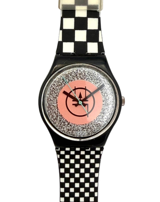 A wristwatch with a black and white checkered strap, a black case, and a glittery silver dial featuring a pink center circle with a black logo.