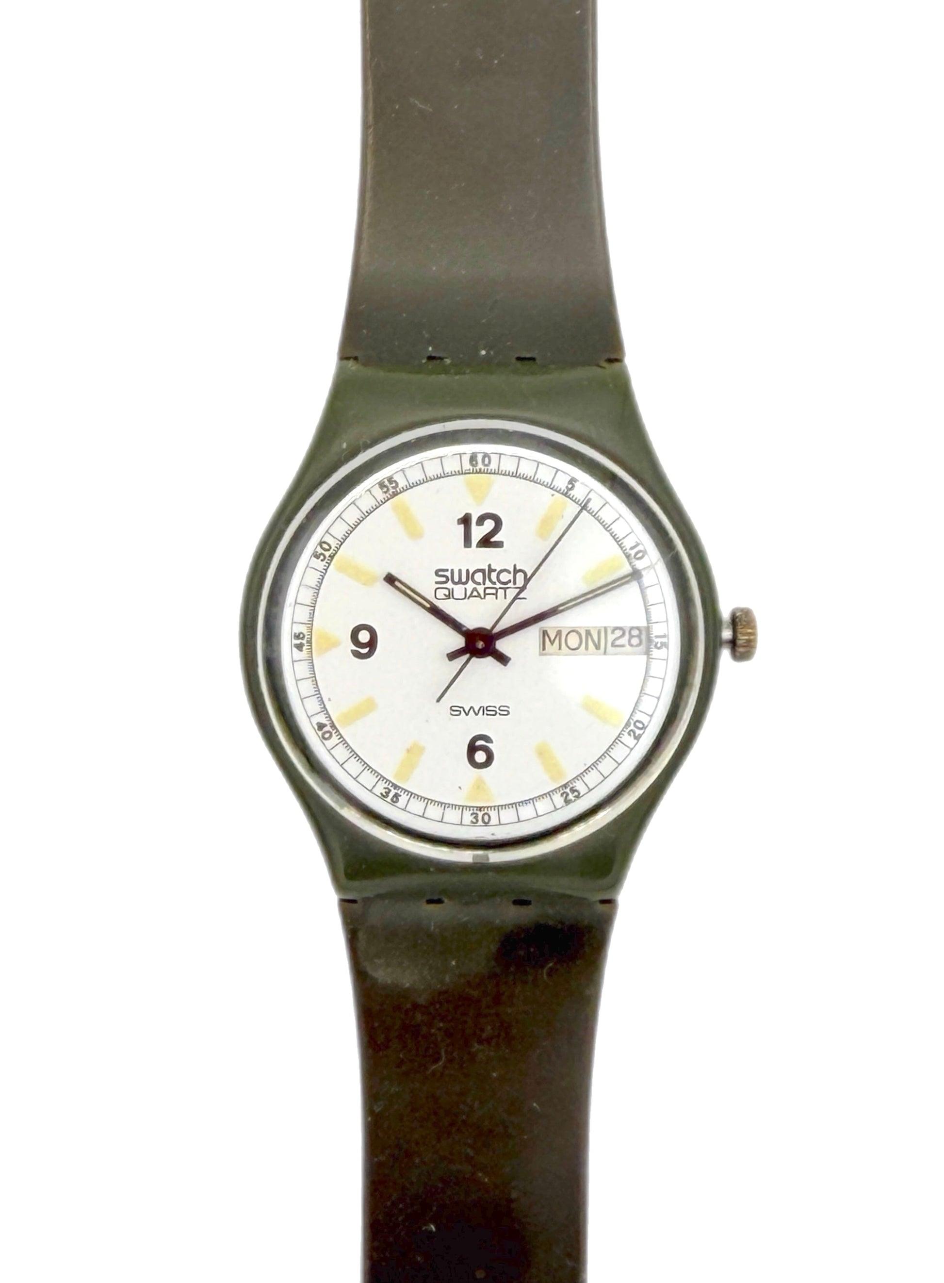 A vintage Swatch Duxx wristwatch with a dark olive green strap and case, featuring a white dial with black Arabic numerals and a day/date window.
